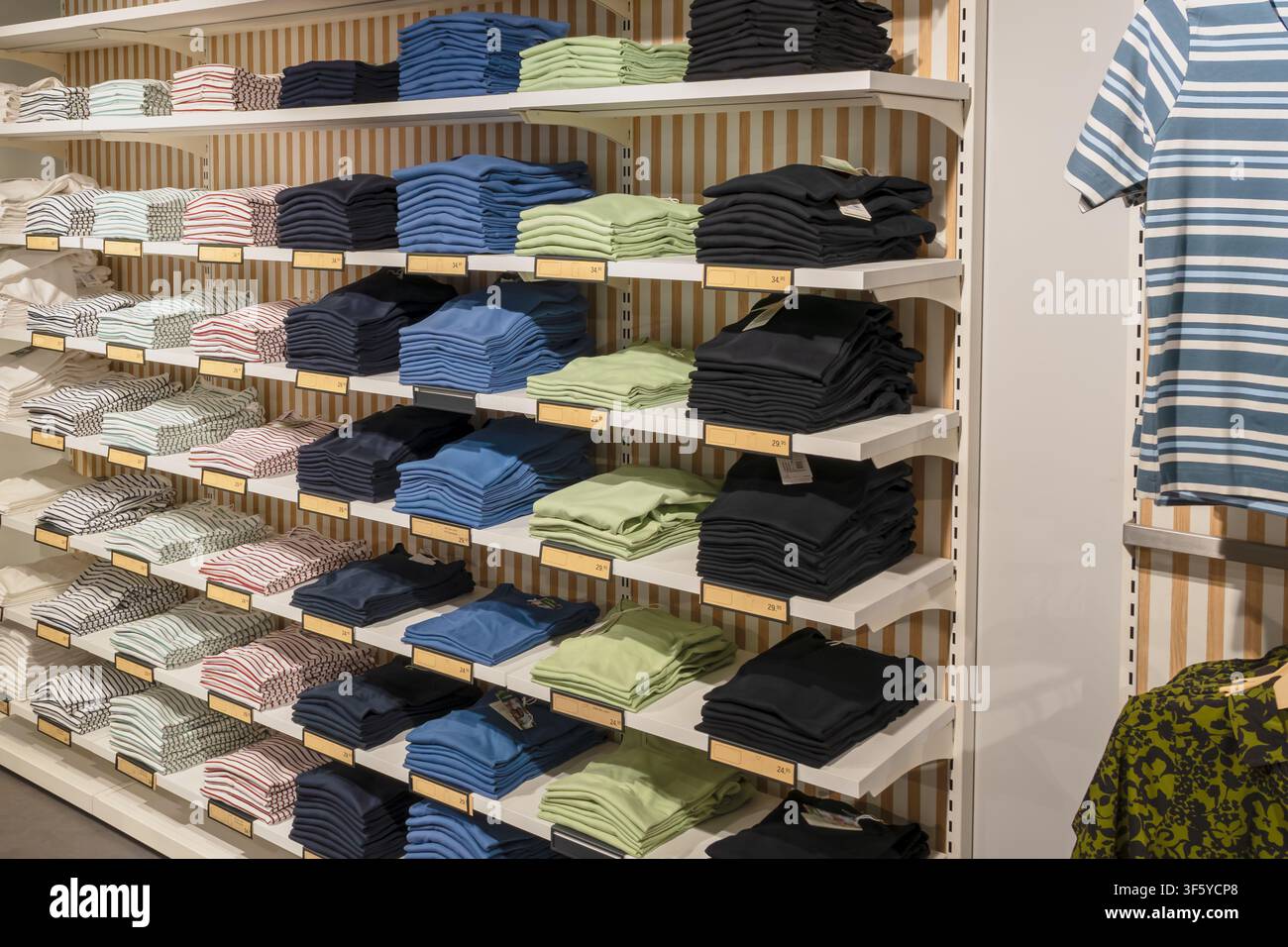 Pile ordinate di camicie casual a righe e a tinta unita esposte su scaffali del negozio, evidenziando il commercio al dettaglio di moda, il visual merchandising, la scelta del prodotto e Foto Stock