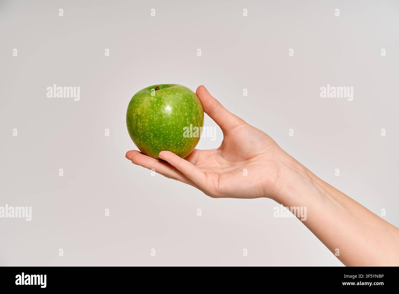Una giovane donna che mostra una mela verde lucida, emanando freschezza e gioia. Foto Stock