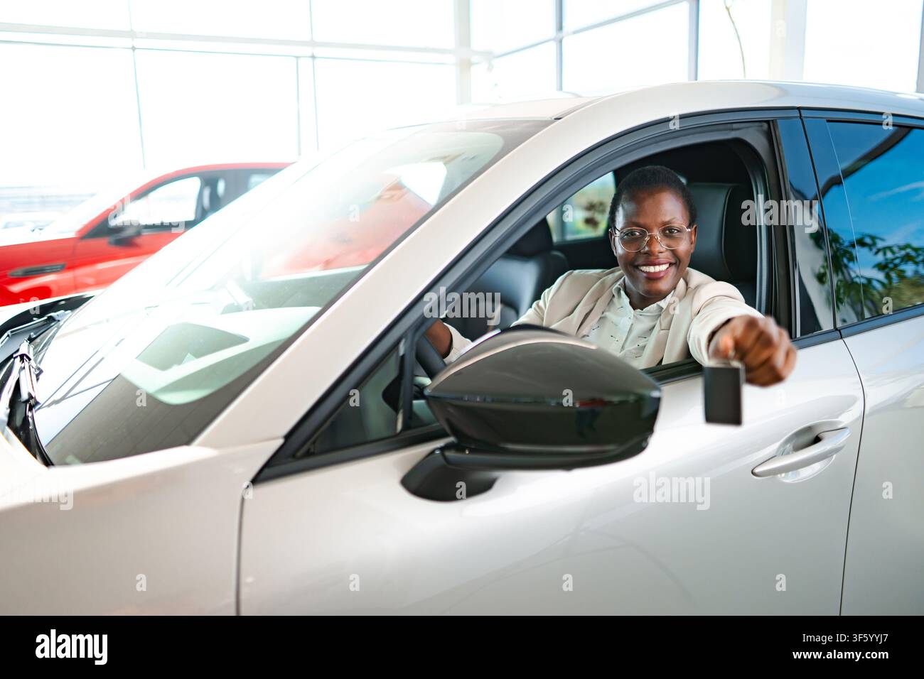Donna felice che tiene la chiave della nuova auto in concessionaria Foto Stock