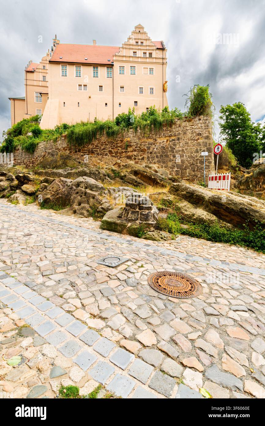 Il castello di Quedlinburg si erge sopra formazioni rocciose di arenaria e una storica strada lastricata a Quedlinburg, Germania. Foto Stock