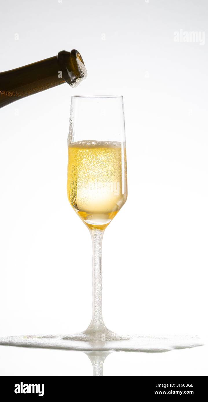 Champagne versata in un bicchiere creando una schiuma che trabocca, celebrando il lusso Foto Stock