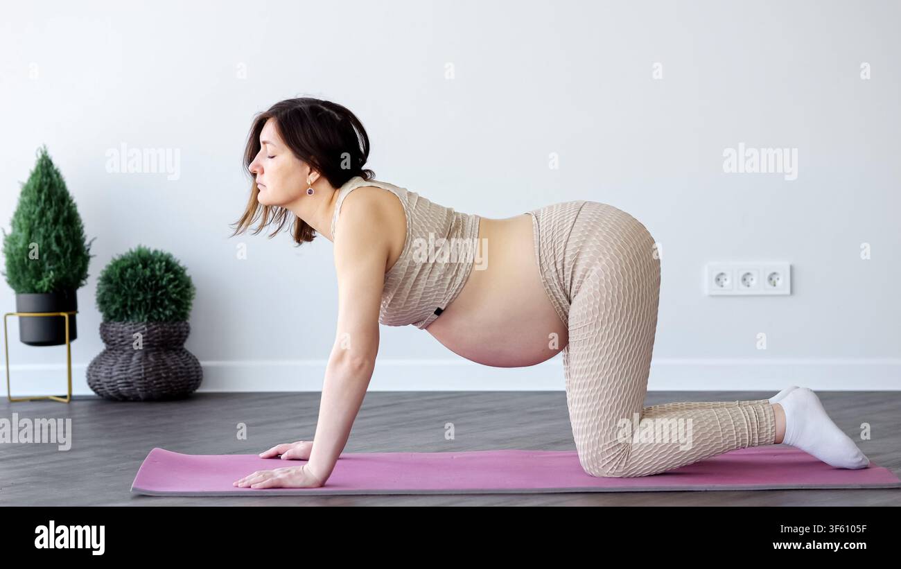 Donna incinta che pratica yoga a casa durante la gravidanza Foto Stock