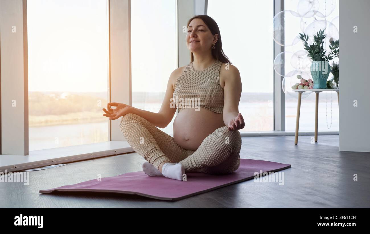Donna incinta che pratica yoga e meditazione per il benessere Foto Stock