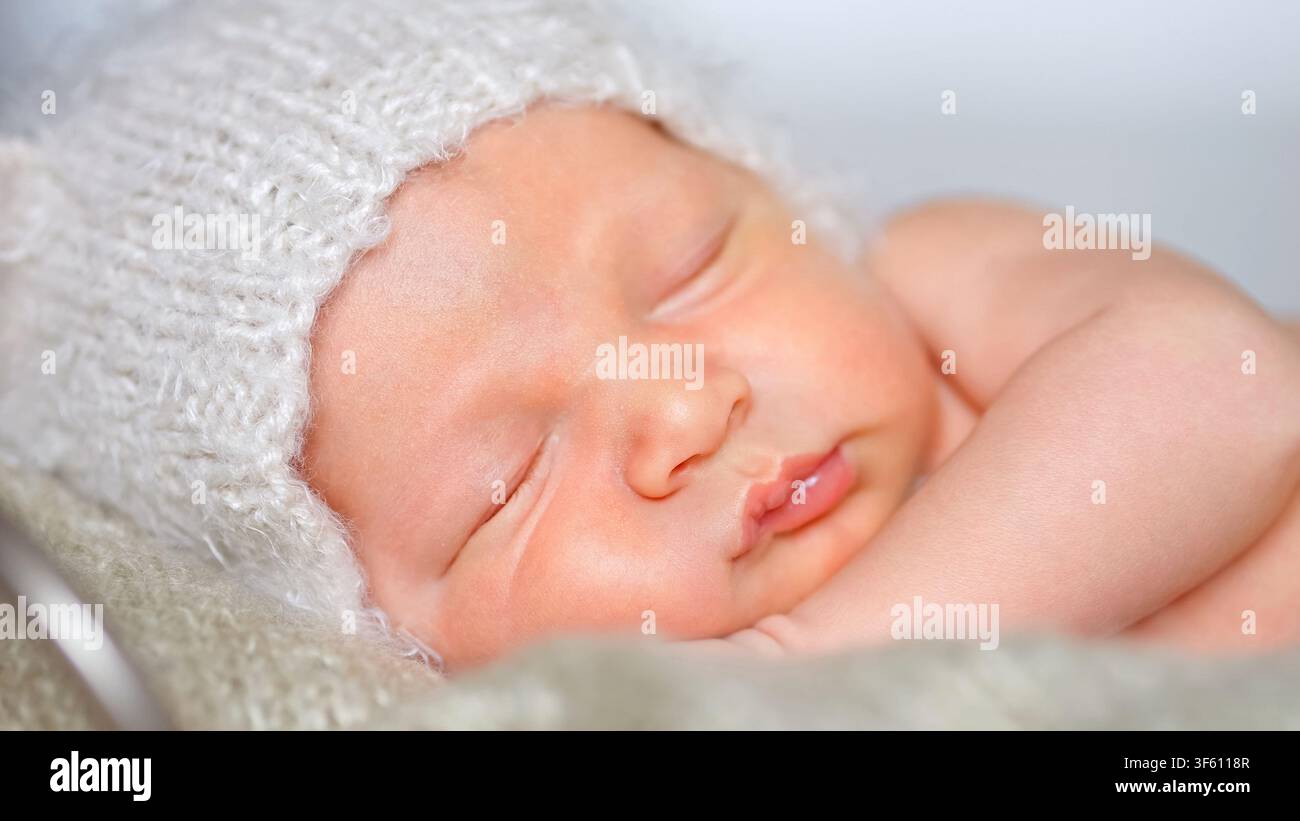 Neonato che dorme pacificamente con un morbido cappello di lana Foto Stock