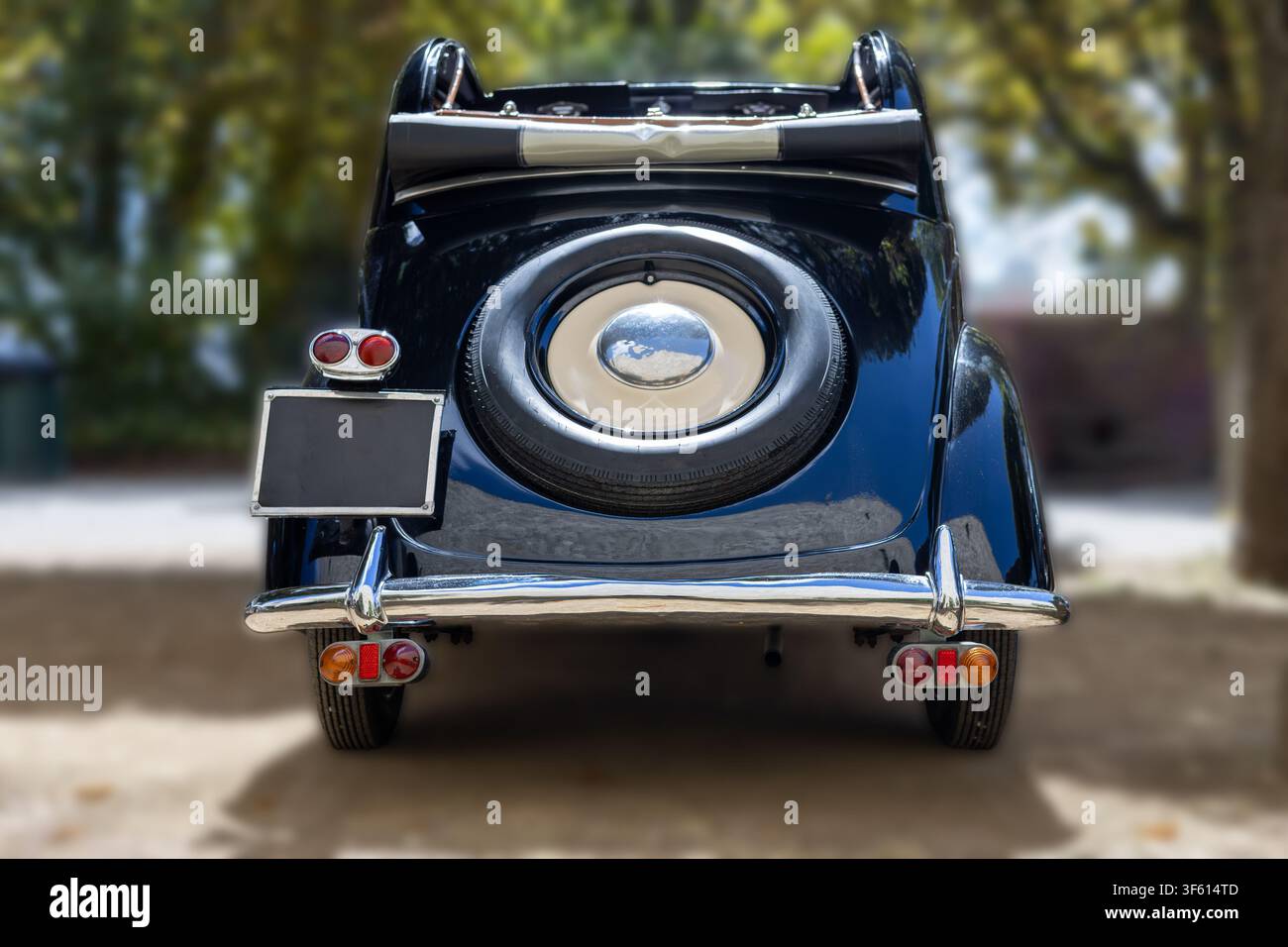 Vista posteriore di un'auto classica vintage nera convertibile con gomma di scorta e paraurti cromato all'aperto. Foto Stock