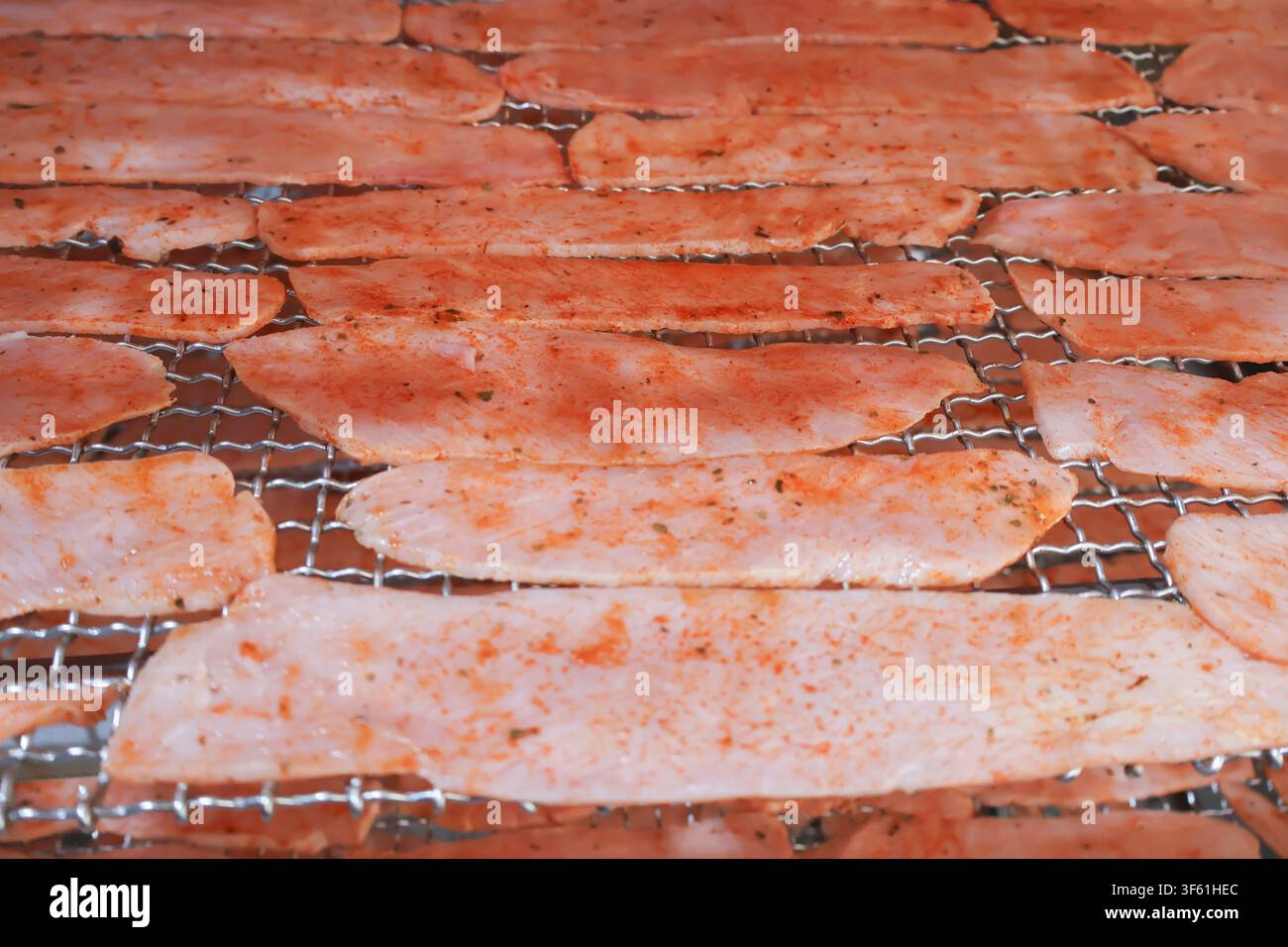 Fette di filetto di maiale stagionato che cuociono su una griglia metallica del forno. Foto Stock