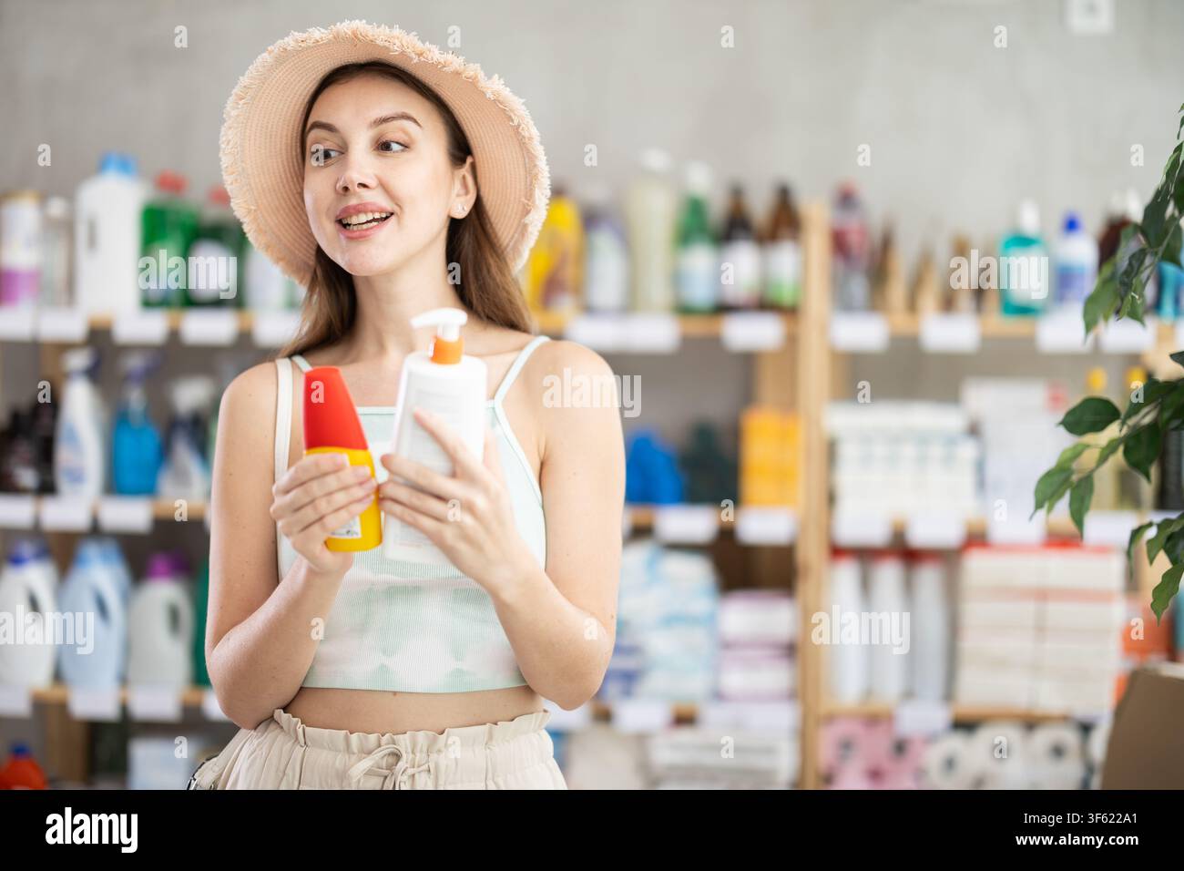 Donna che sceglie prodotti abbronzanti e crema solare al supermercato Foto Stock