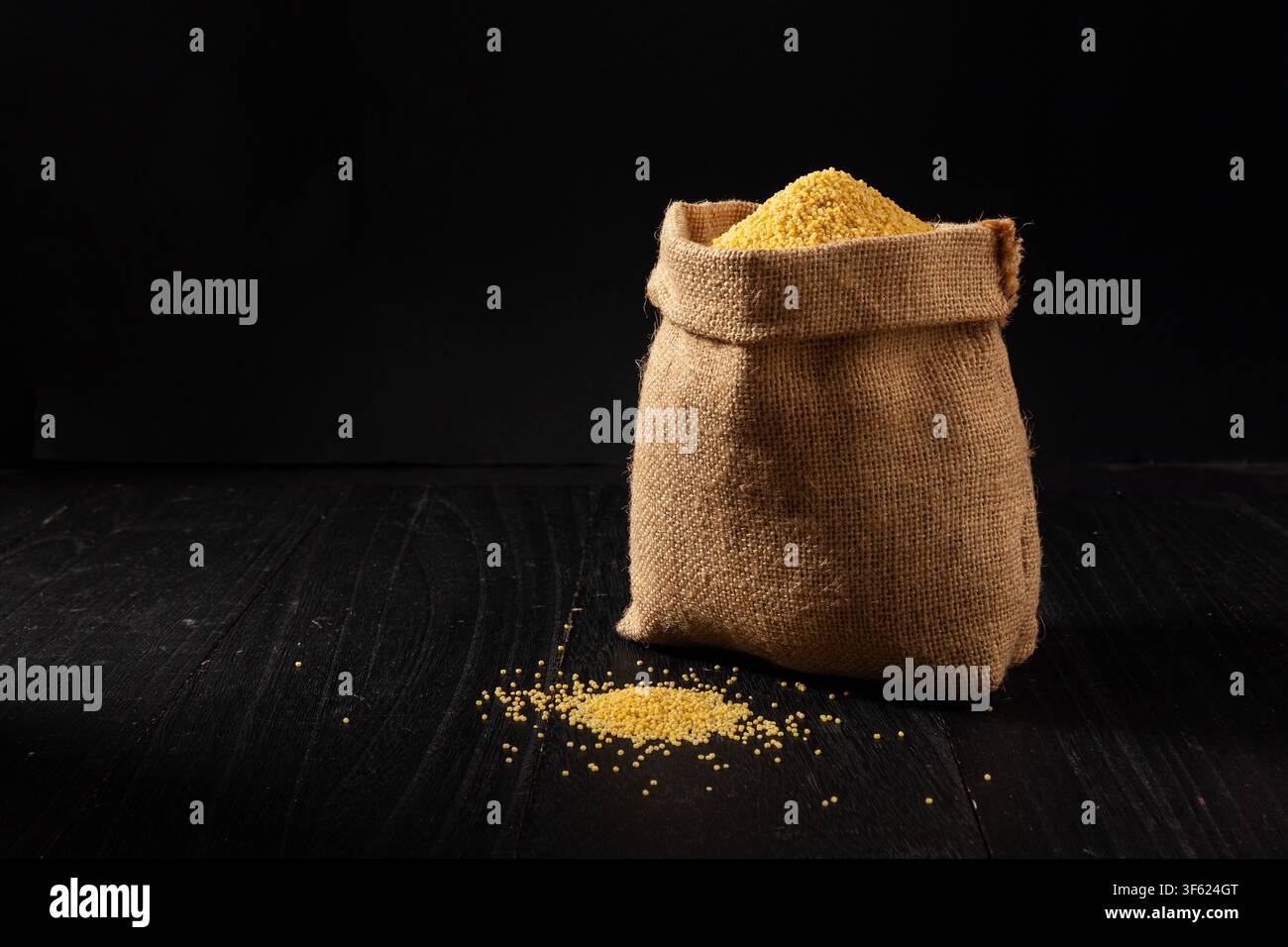 Granelli di miglio giallo crudo in un sacco di iuta Foto Stock