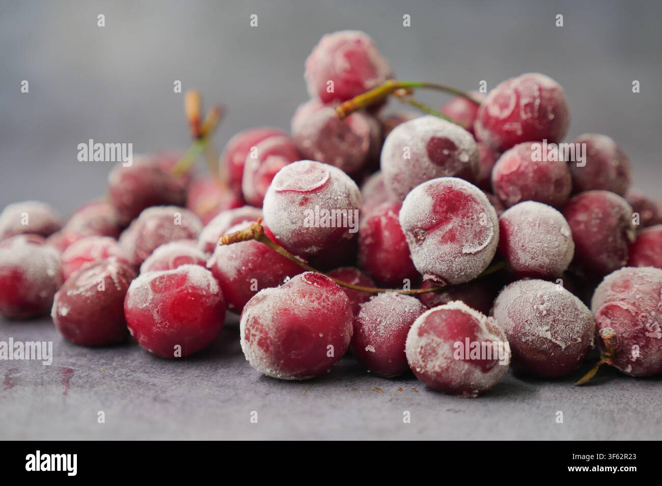 Ciliegie rosse congelate su una superficie scura Foto Stock