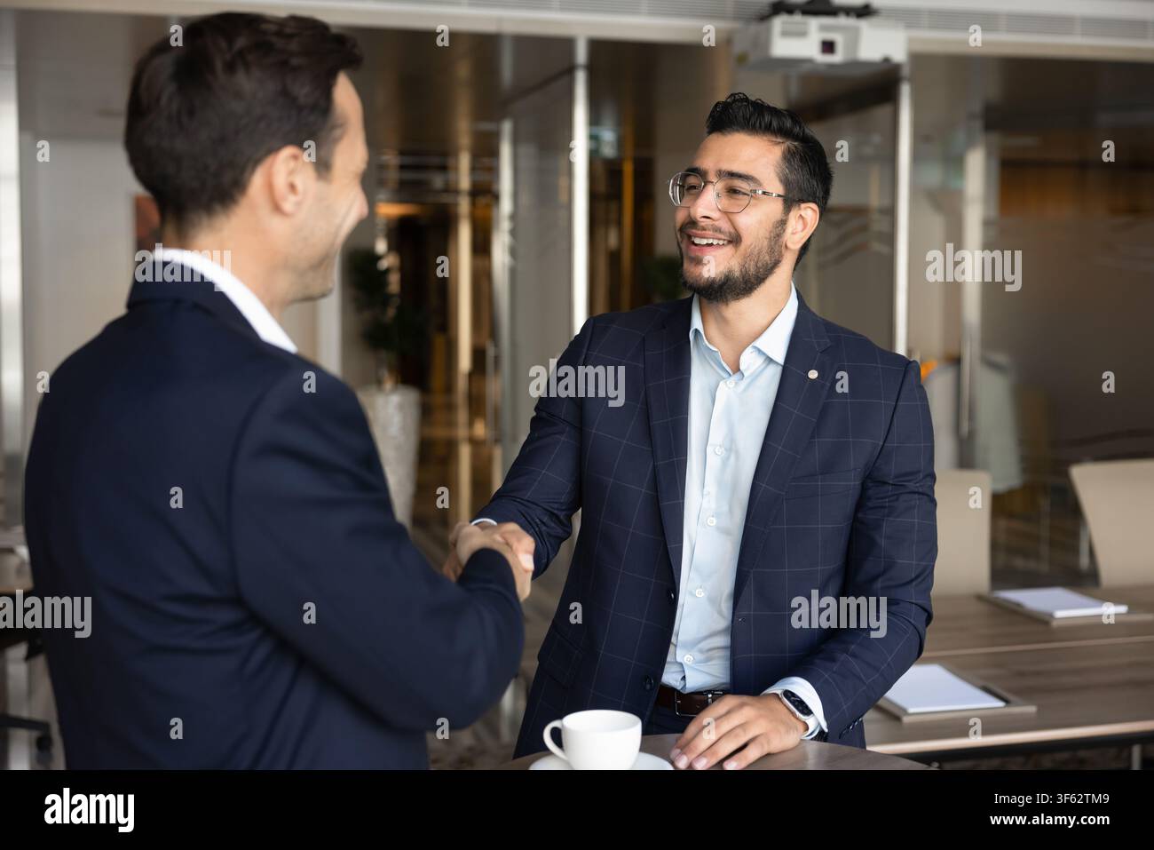 Due uomini d'affari multietnici che si stringono la mano in un ufficio aziendale Foto Stock