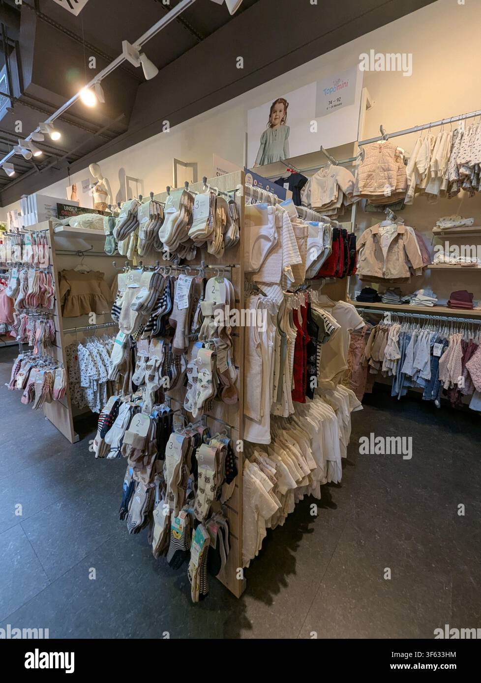 Pforzheim Germania 3 agosto 2026 Una presentazione pulita e organizzata di abbigliamento per bambini nell'interno di un negozio, con scaffali e espositori, che mostra calzini per bambini Foto Stock