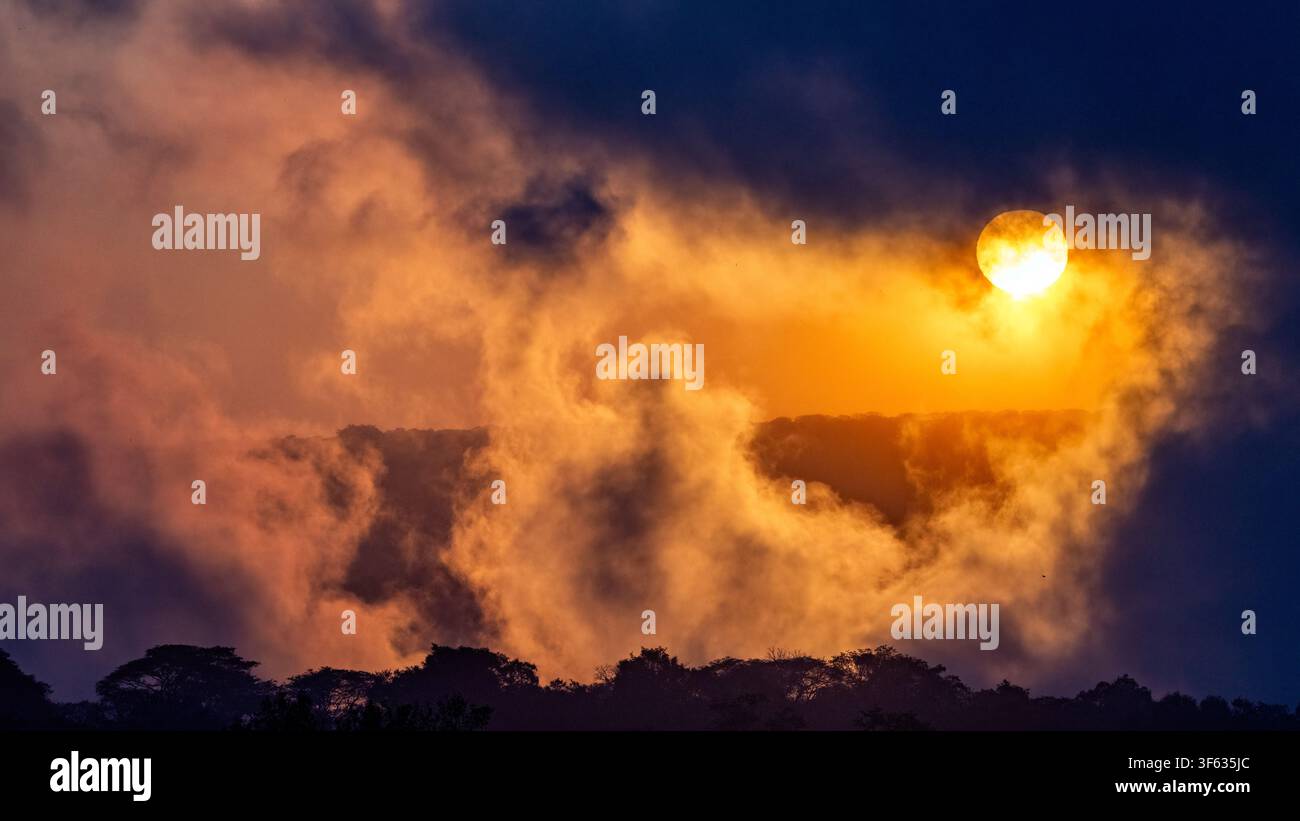Nuvole di nebbia tonante e fumo delle Cascate Victoria all'alba - Cascate Victoria, Zimbabwe Foto Stock