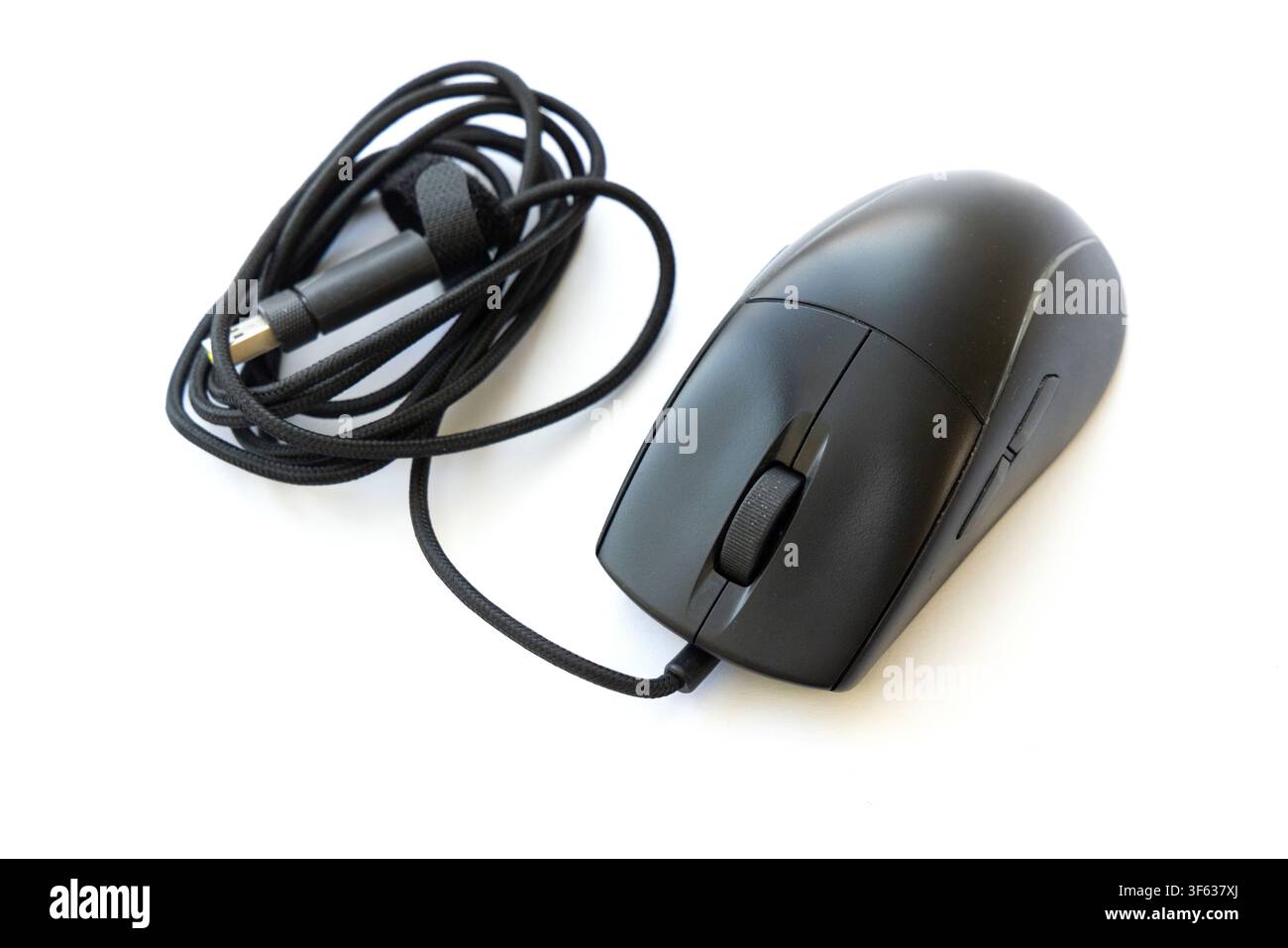 Un mouse da computer nero con cavo intrecciato ordinatamente avvolto poggia su una superficie bianca pulita Foto Stock