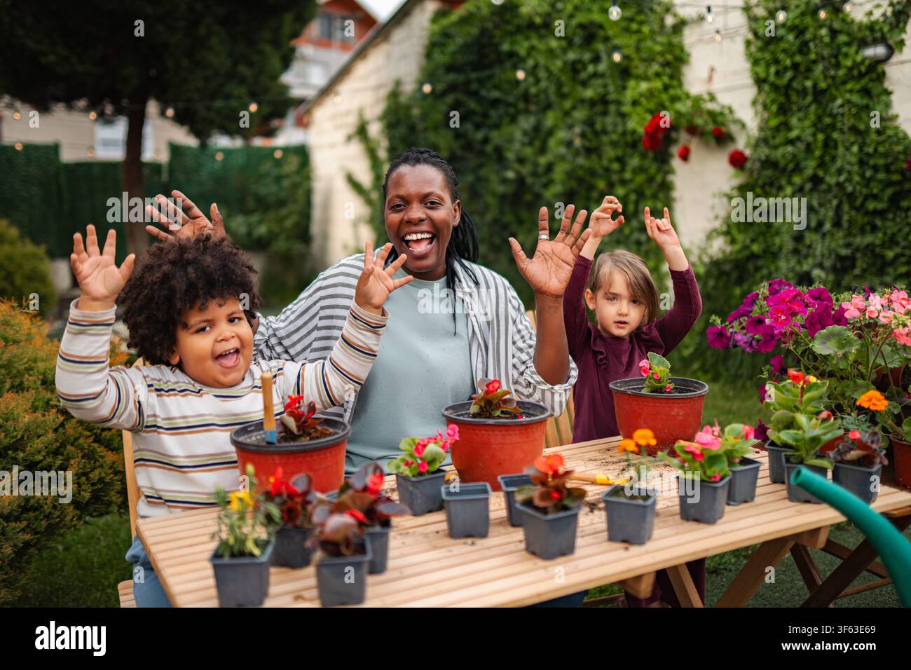 Famiglia diversificata che fa giardinaggio nel cortile posteriore e si diverte a piantare fiori Foto Stock
