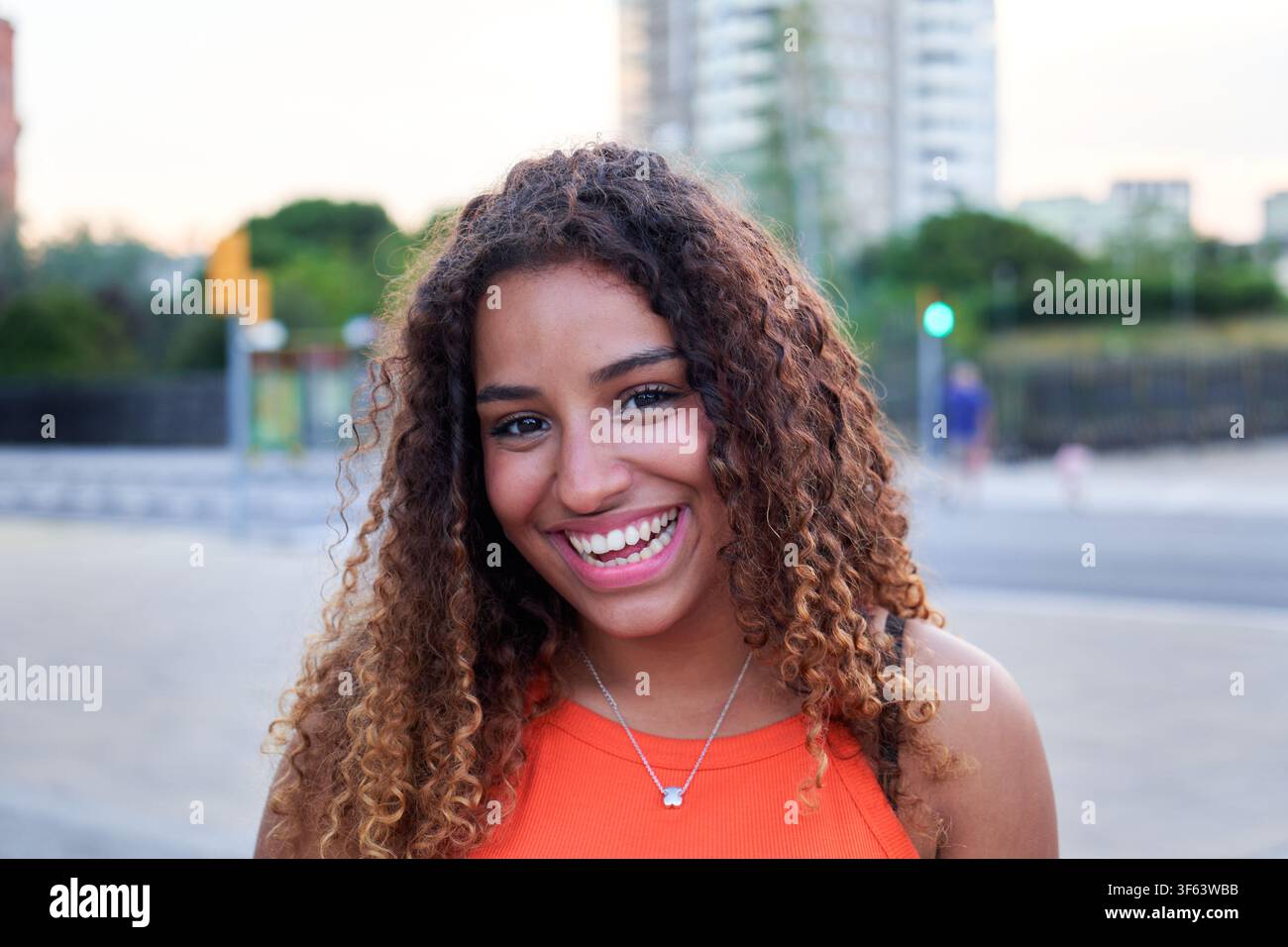 Giovane donna nera sorridente all'aperto in un ambiente urbano. Foto Stock