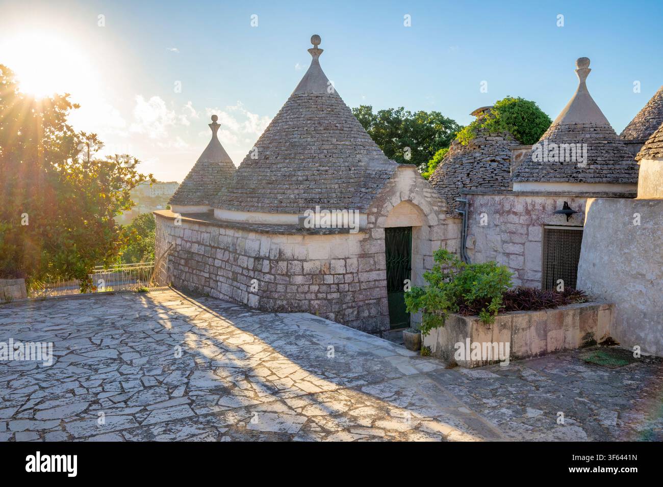 Trulli tradizionali immersi nel caldo bagliore dell'alba, che rivelano il fascino senza tempo delle iconiche abitazioni in pietra calcarea della valle d'Itria. Contrada Ritunno, Locorotondo, Provincia di Bari, Puglia, Italia Foto Stock