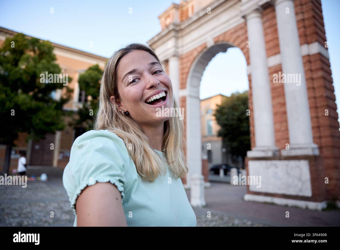 Giovane donna sorridente davanti ad un arco in mattoni Foto Stock