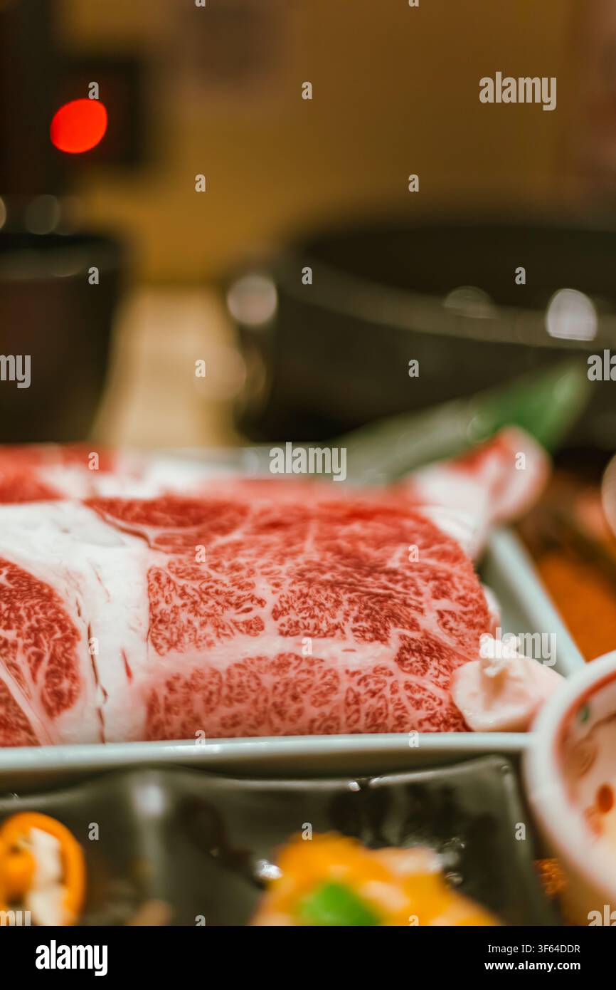 Un'immagine dettagliata in primo piano di carne Wagyu giapponese a fette su un piatto di ceramica preparato per lo Shabu Shabu Foto Stock