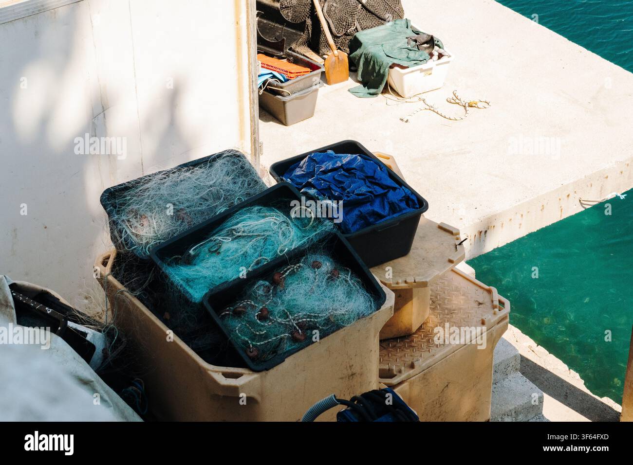 Reti da pesca e contenitori disposti sul ponte di una barca da pesca lavorativa. Attrezzature per la pesca commerciale preparate per le operazioni marittime quotidiane. Foto Stock
