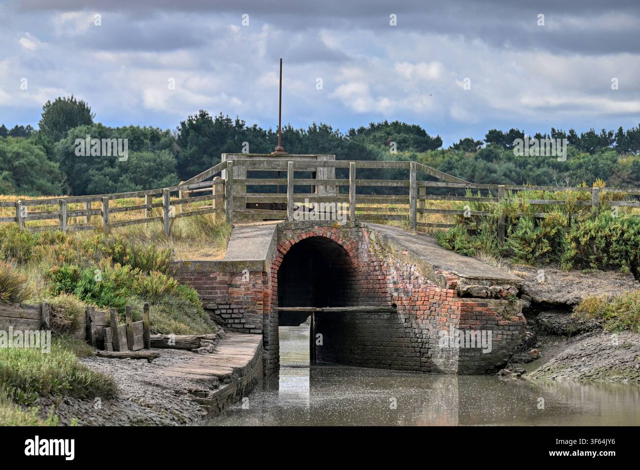 Chiavica di marea che aiuta a controllare i livelli dell'acqua al Thornham Harbour, Norfolk, Regno Unito Foto Stock