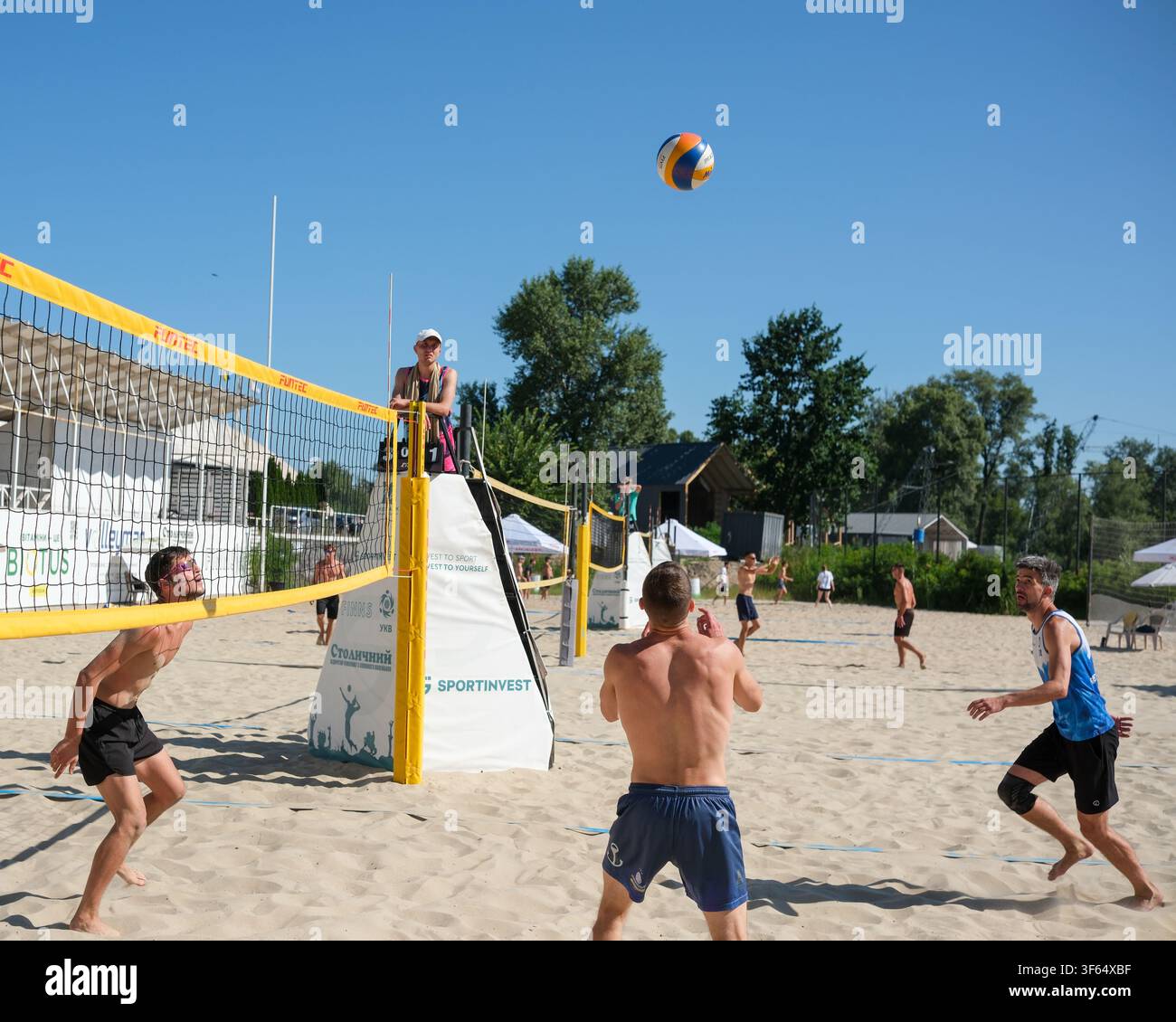 KIEV, UCRAINA – 25 luglio 2026: I giocatori di beach volley si posizionano per il prossimo touch durante un torneo estivo competitivo mentre la palla trav Foto Stock
