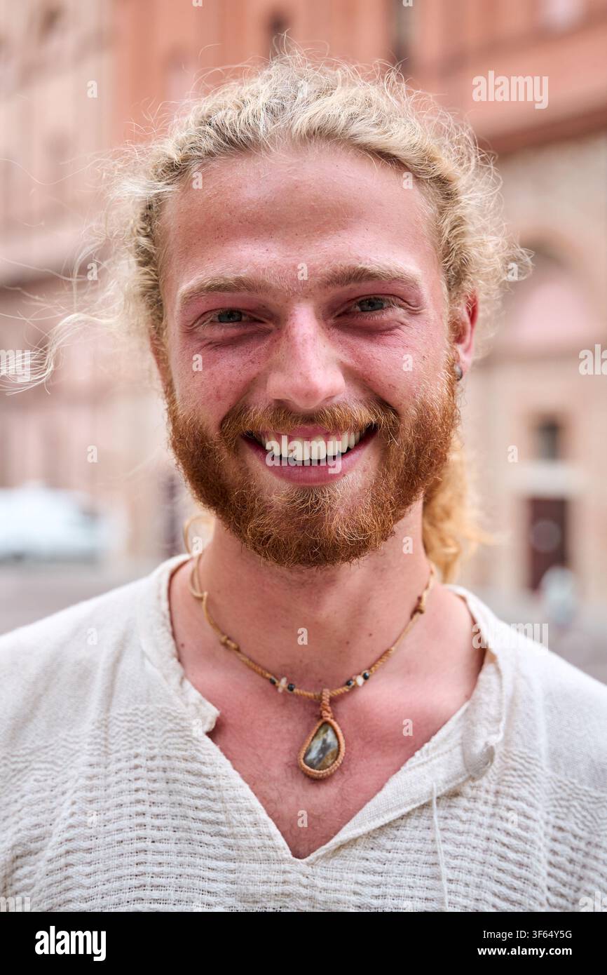 Ritratto di un attraente giovane sorridente che guarda la macchina fotografica nel parco. Bel modello maschile caucasico. Foto Stock