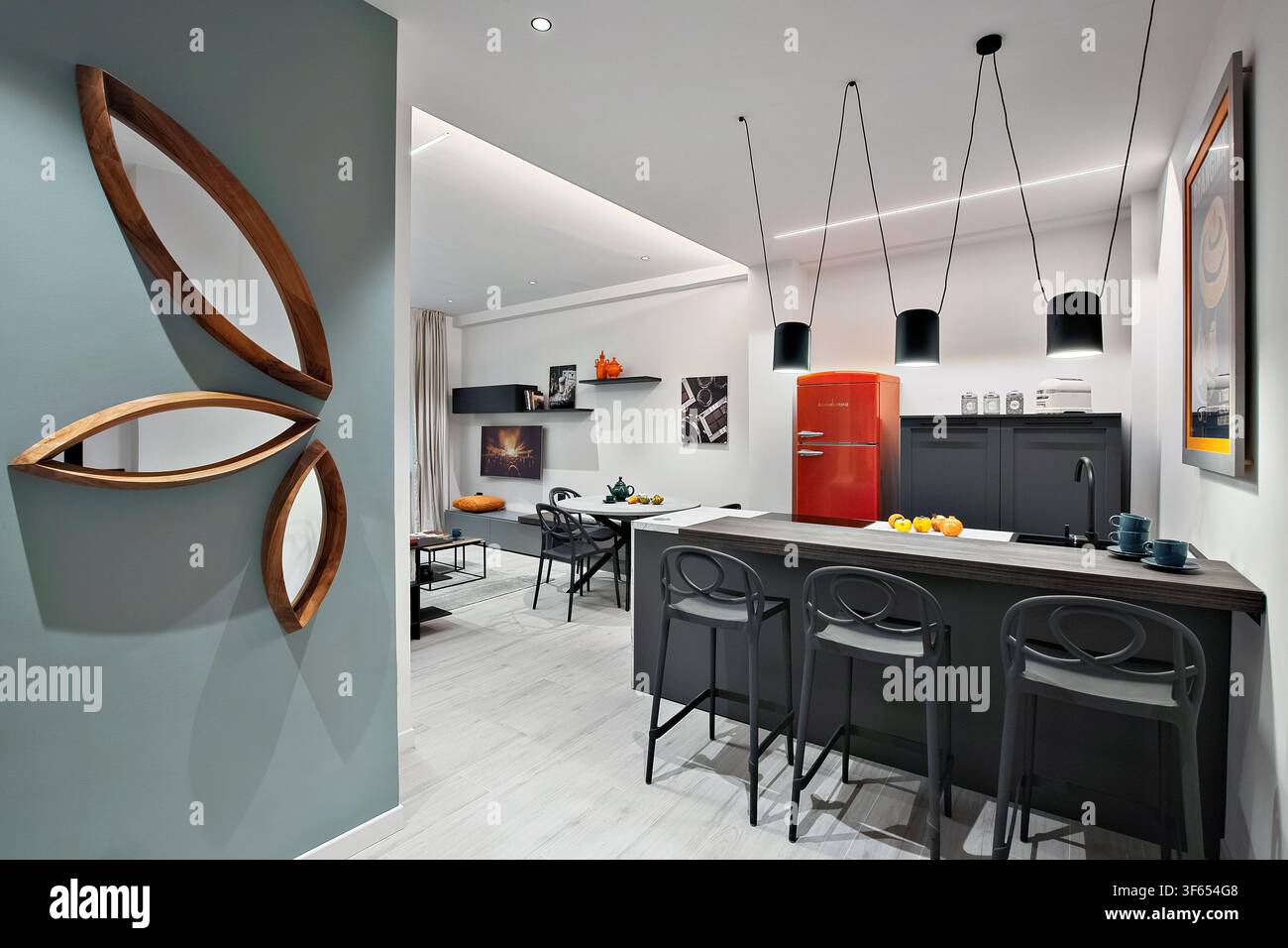 Cucina contemporanea in un appartamento di Torino convertito da ufficio a uso residenziale, con isola, lampade a sospensione, frigorifero rosso e specchio decorativo Foto Stock