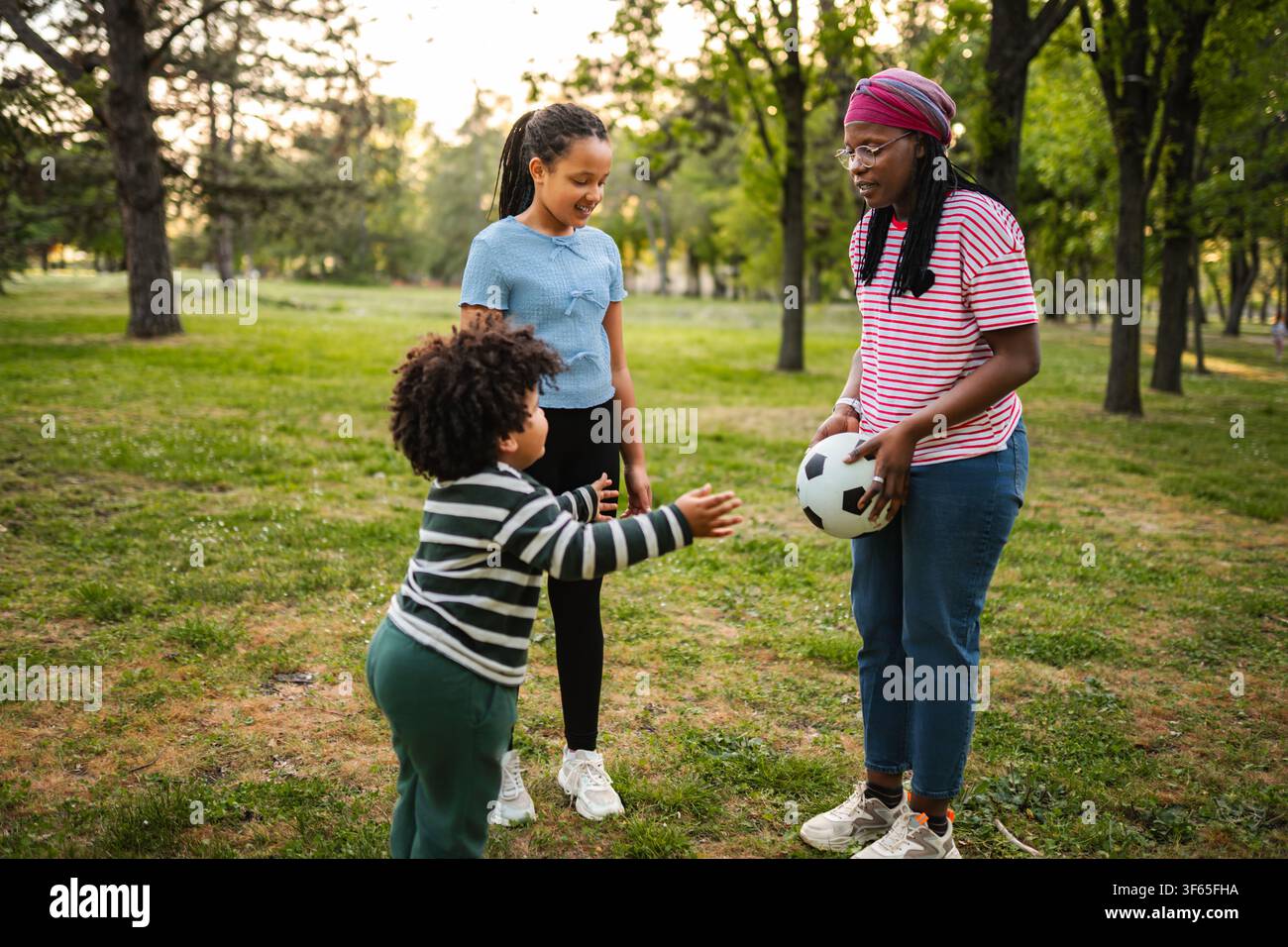 Famiglia che gioca a calcio e si gode il tempo libero nel parco Foto Stock