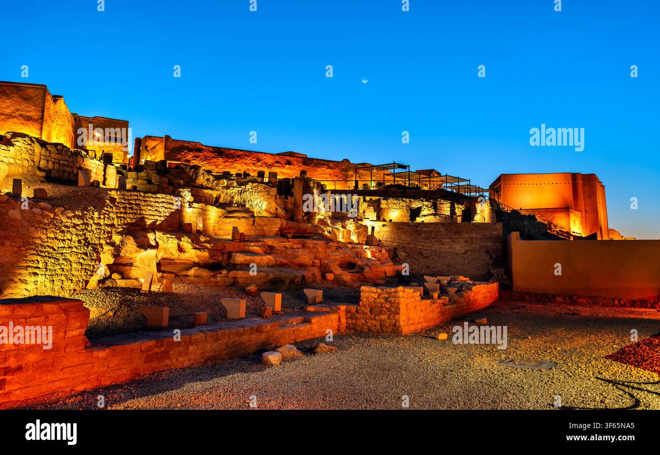 Le antiche rovine del sito storico di At-Turaif illuminate di notte sotto un cielo blu sereno a Diriyah, in Arabia Saudita. Foto Stock