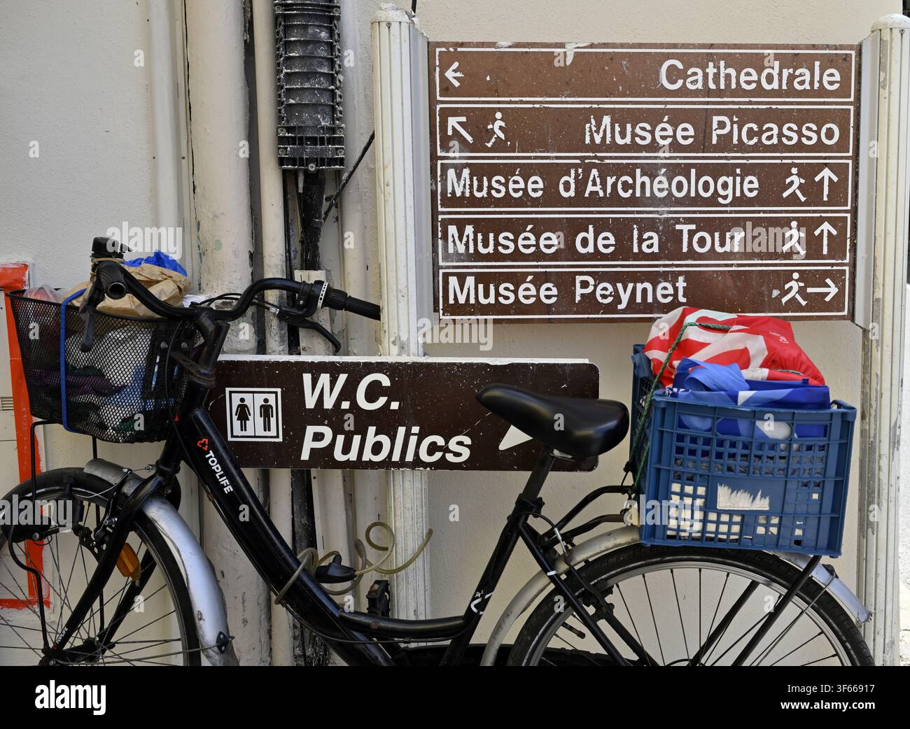 Segnale informativo di Antibes per i servizi igienici pubblici e il museo Picasso, altri con bicicletta davanti, Francia Foto Stock