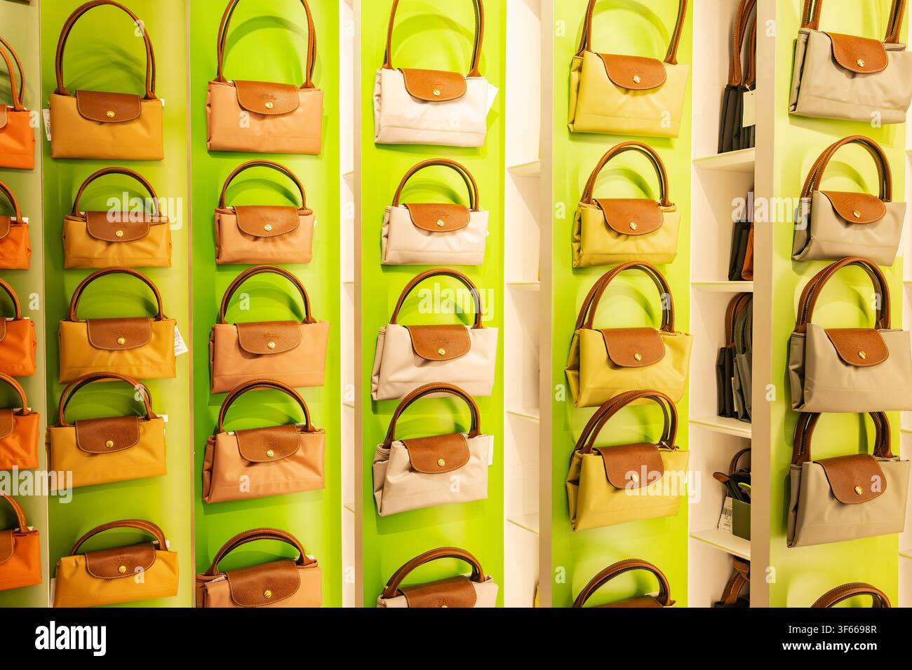 Parigi, Francia - 5 luglio 2026: File colorate di iconiche borse tote in nylon pieghevoli Longchamp Le Pliage appese a una parete espositiva verde brillante di una boutique Foto Stock