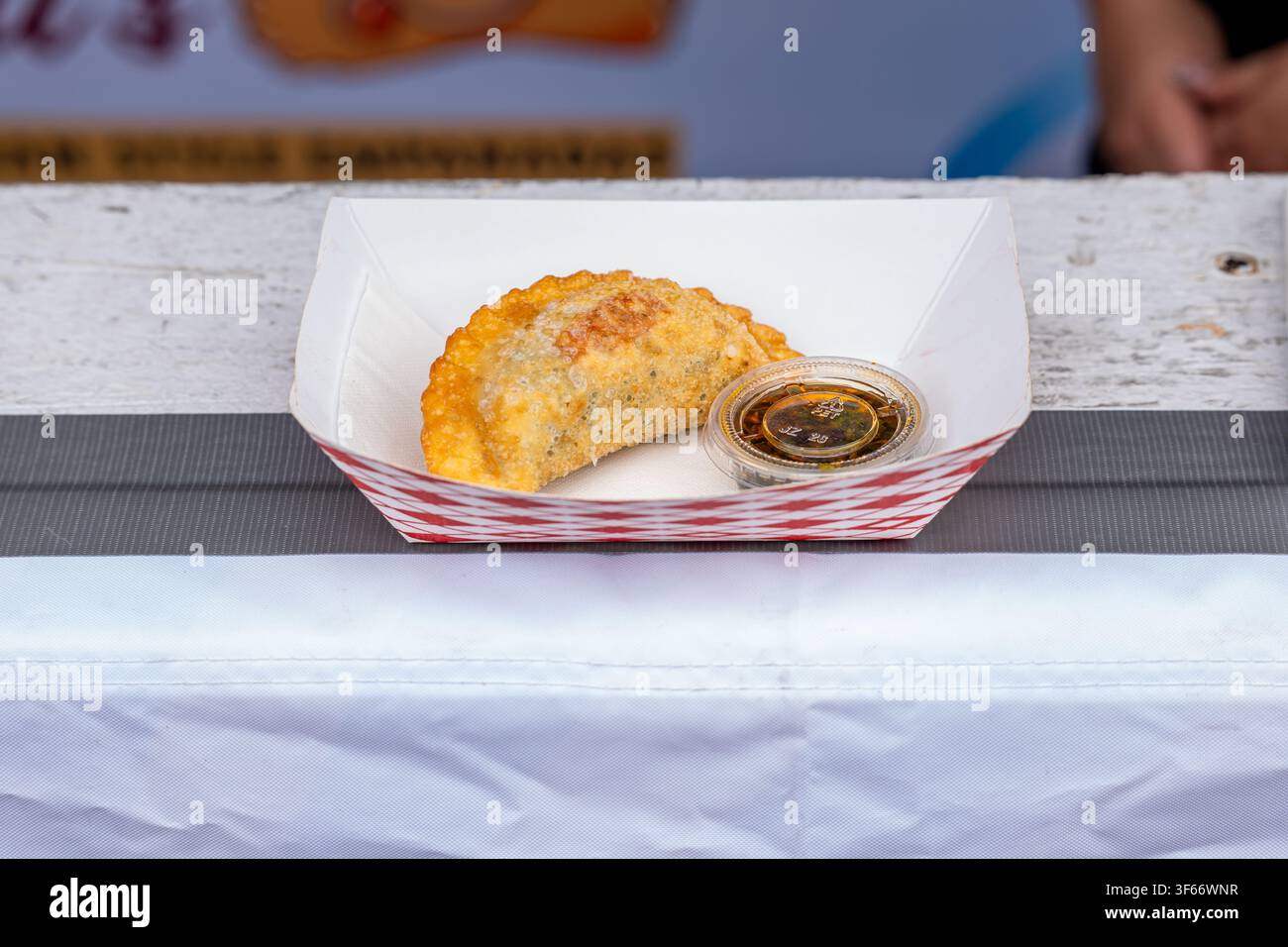 Un'empanada dorata appena fritta servita con salsa da intingere in un vassoio di carta al festival Taste of Chicago. Foto Stock