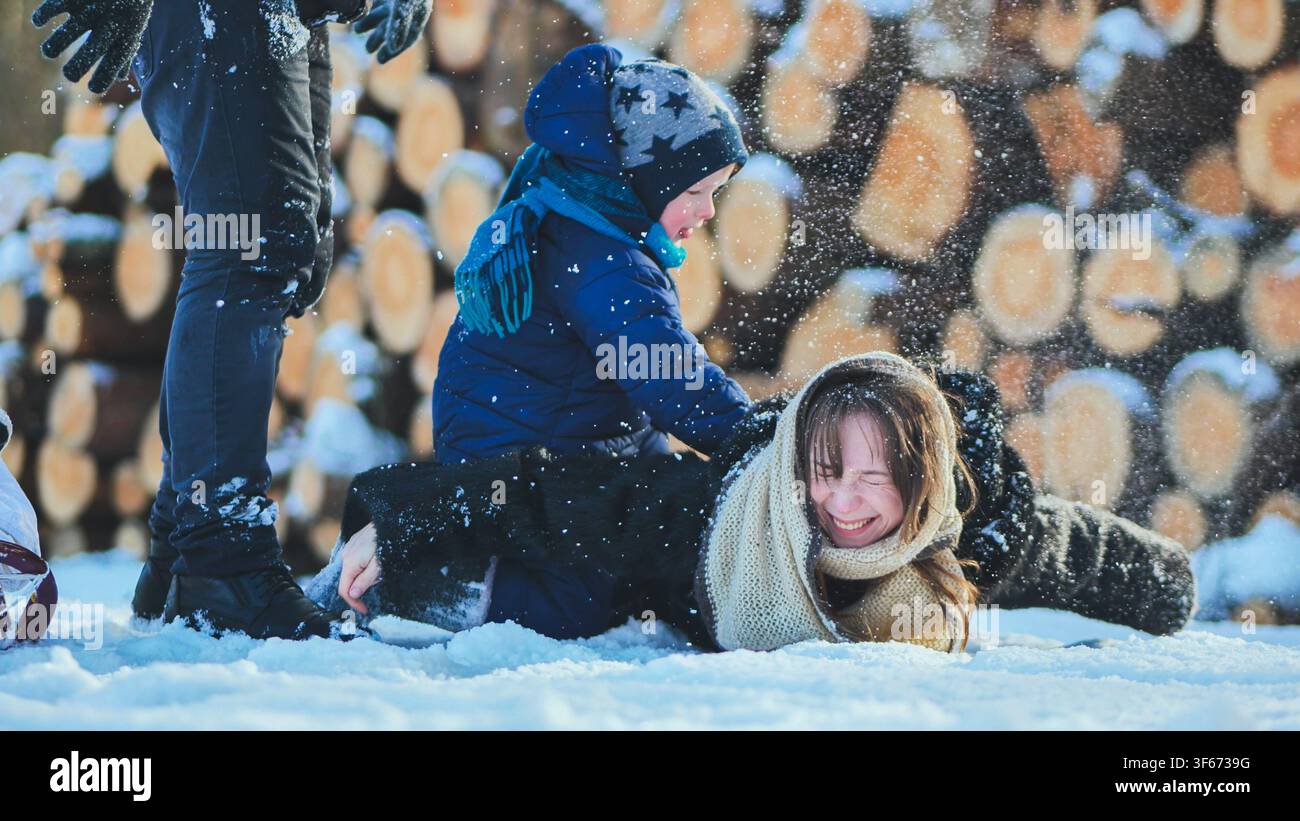 Famiglia felice che gioca nella neve in una bella giornata invernale, godendosi del tempo di qualità insieme Foto Stock