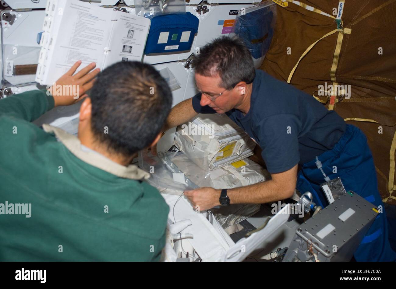 Astronauti Stephen Robinson e Soichi Noguchi sul middeck dello Space Shuttle durante la missione STS-114, una missione del programma della navetta spaziale della NASA nel 2005, guidata da Robinson come specialista di missione e Noguchi come specialista di missione, con Robinson veterano di quattro missioni dello Space Shuttle. Foto Stock