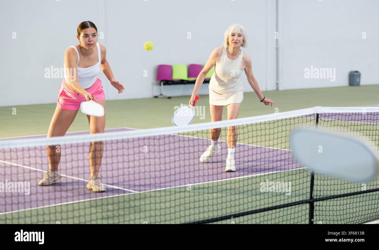 Donne che giocano a Pickleball tennis sul campo da Pickleball al coperto Foto Stock