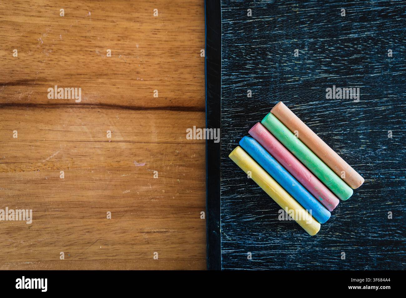 Concetto di design educativo creativo: matite colorate, gesso e lavagna di legno per il ritorno a scuola su un tavolo di legno Foto Stock