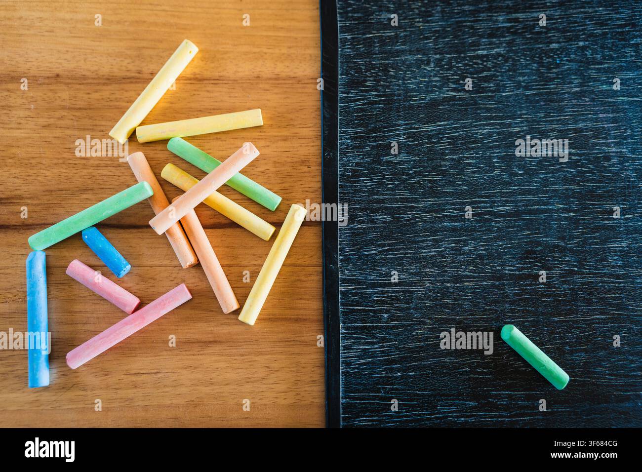 Concetto di design educativo creativo: matite colorate, gesso e lavagna di legno per il ritorno a scuola su un tavolo di legno Foto Stock