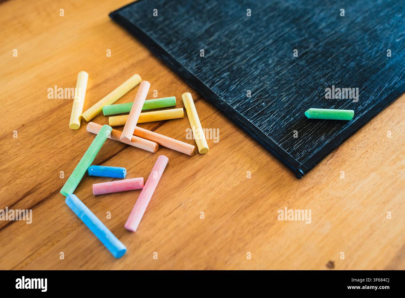 Concetto di design educativo creativo: matite colorate, gesso e lavagna di legno per il ritorno a scuola su un tavolo di legno Foto Stock