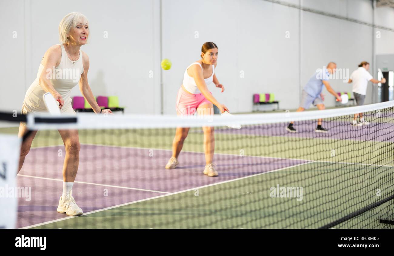 Donne che giocano a Pickleball tennis sul campo da Pickleball al coperto Foto Stock