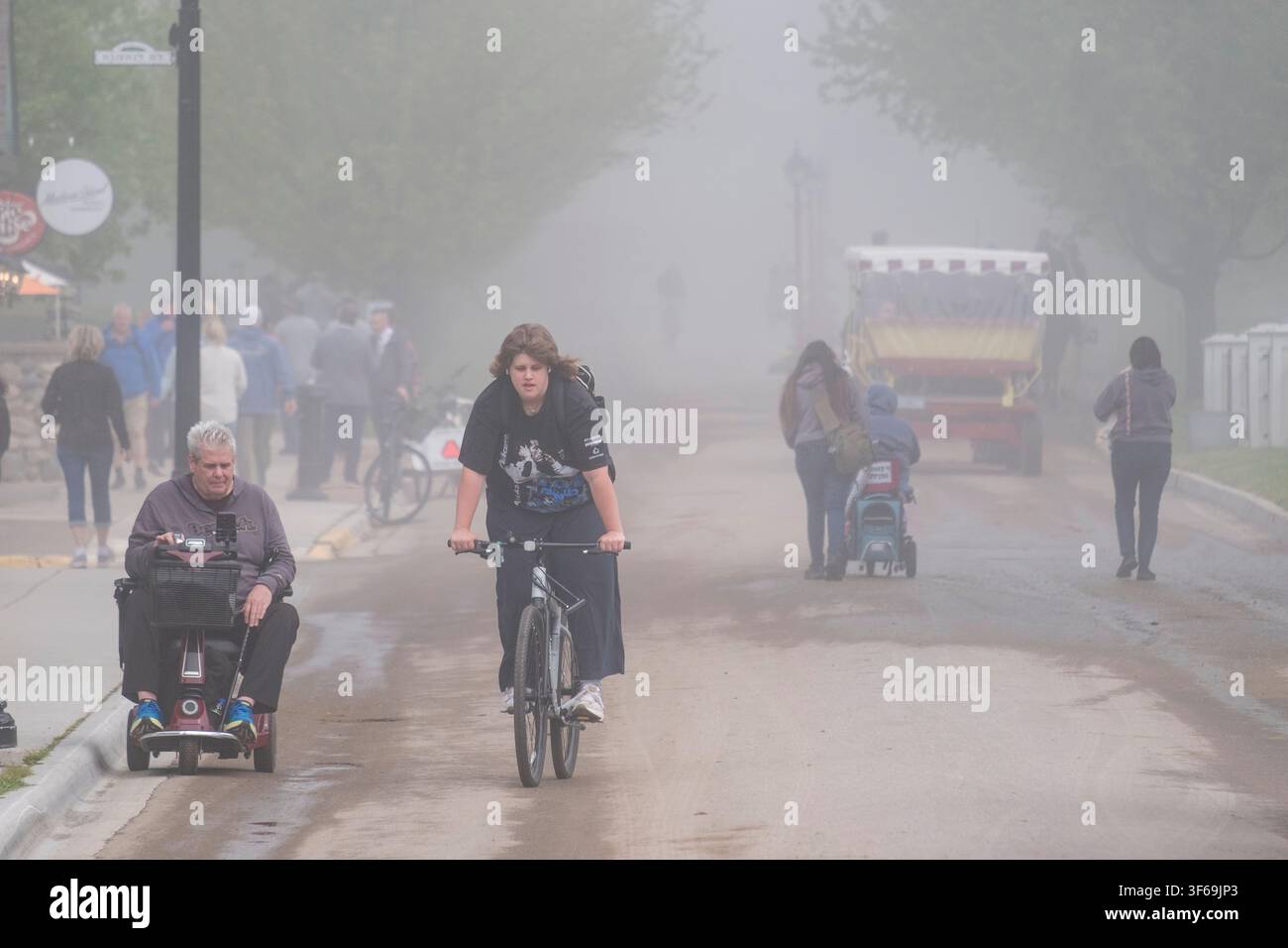 Un velo di nebbia si stende su Cadotte Avenue a Mackinac Island, Michigan, creando un'atmosfera serena in questa destinazione storica. I visitatori esplorano la Foto Stock