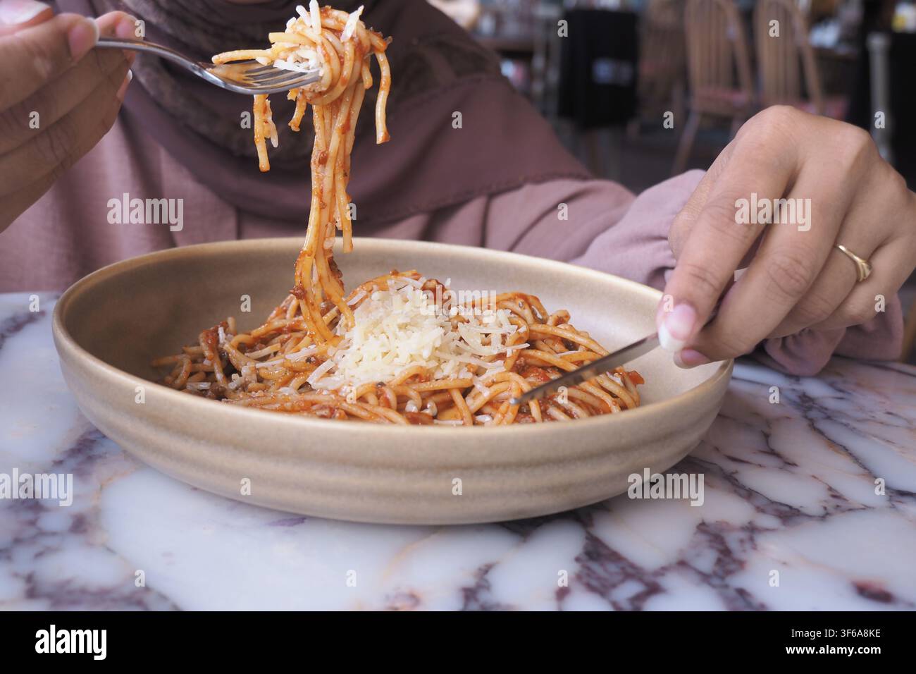 Una persona gusta la pasta in una ciotola al ristorante Foto Stock