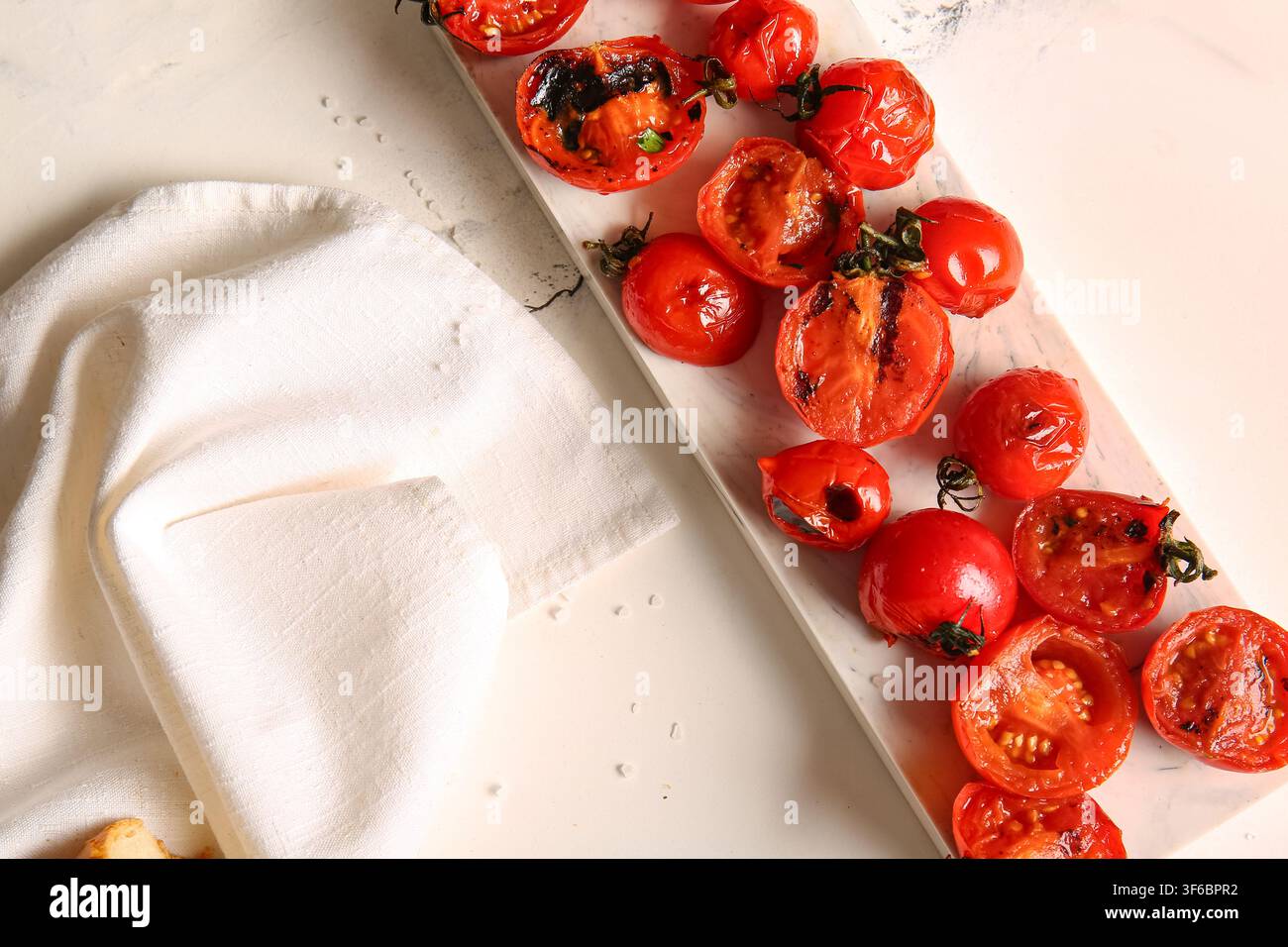 Tavola con gustosi pomodori alla griglia su sfondo bianco Foto Stock