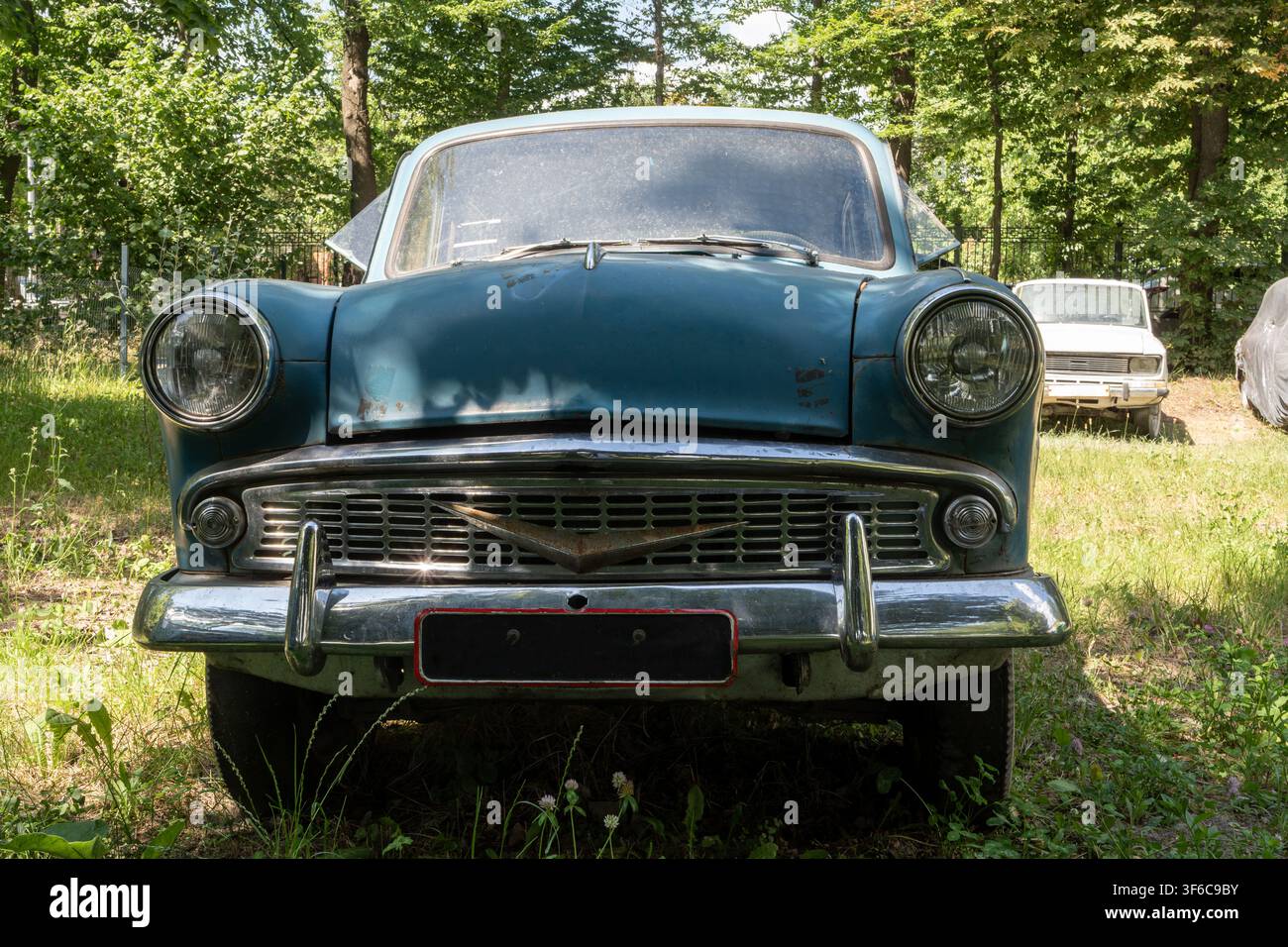 Vecchia berlina retrò blu con classica griglia cromata e fari rotondi si trova sull'erba in un parco estivo soleggiato. Foto Stock