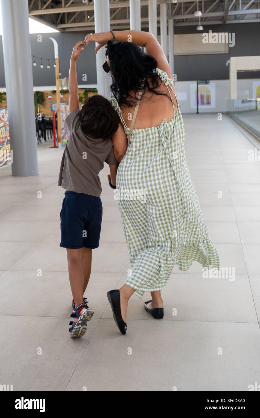 Madre e figlio si legano mentre passeggiano e fanno un gesto a forma di cuore Foto Stock