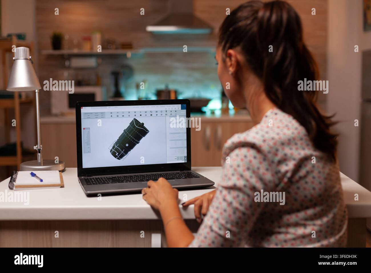 Un professionista tecnico studia progettazione meccanica da casa mentre perfeziona un concetto di turbina industriale sullo schermo. Foto Stock