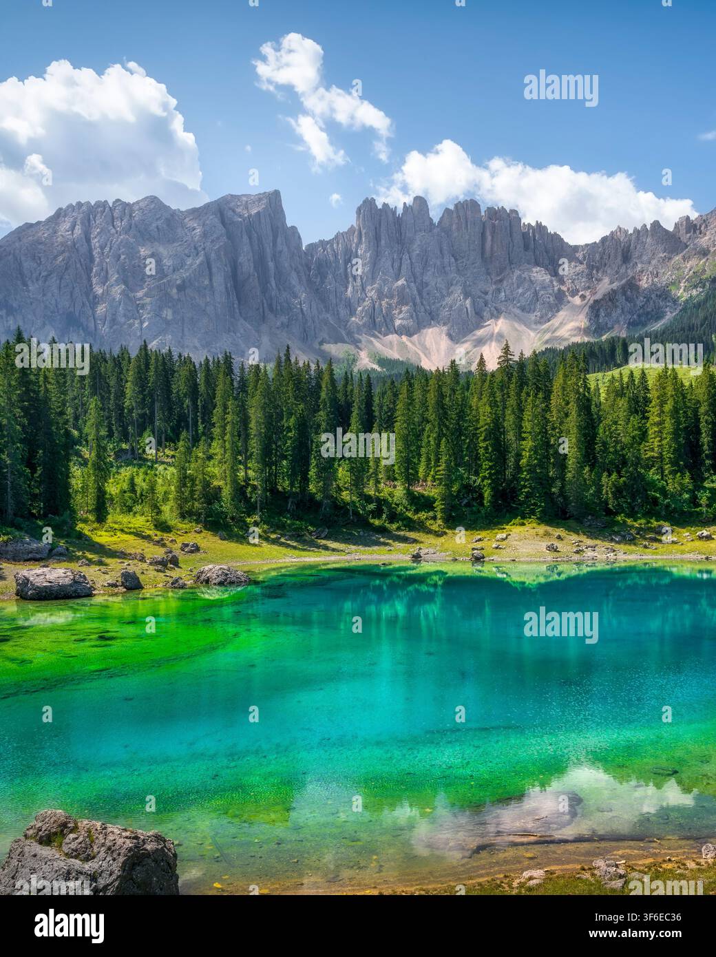 Vista verticale del Lago di Carezza con riflessi specchianti, foresta di pini e vette rocciose del Latemar. Nova Levante, Alto Adige, Dolomiti, Italia Foto Stock