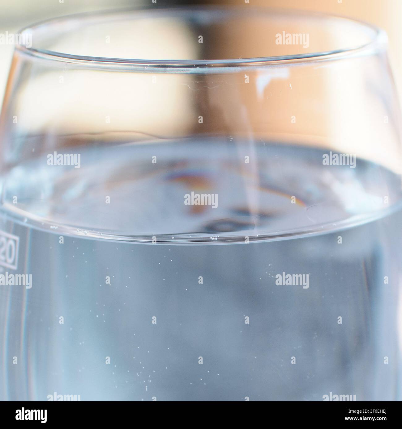 Un primo piano di acqua ferma contenuta in un bicchiere di vetro trasparente, che mostra una superficie liquida calma e una qualità trasparente per la salute e l'idratazione Foto Stock