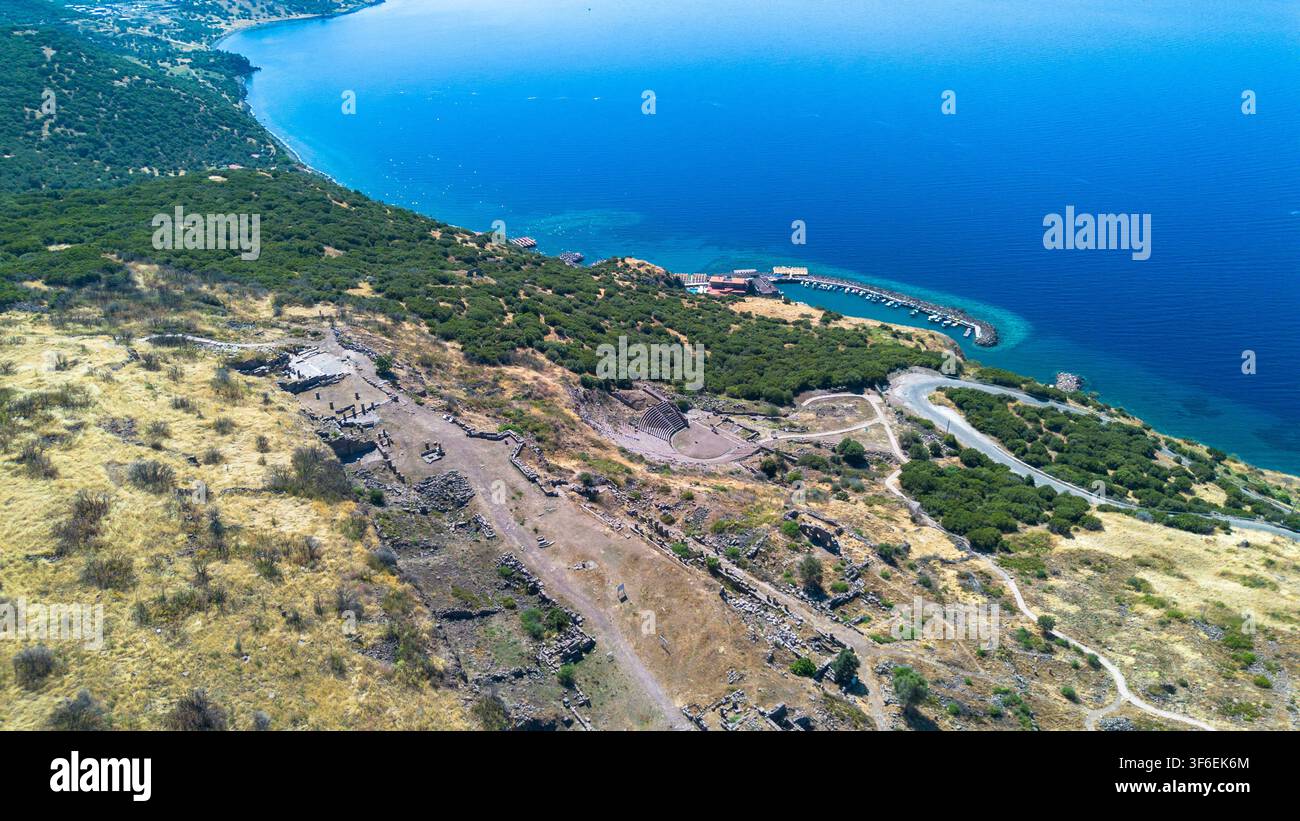 Vista aerea con drone dell'antico teatro di Assos che si affaccia sul mare Egeo blu e sul porto Foto Stock