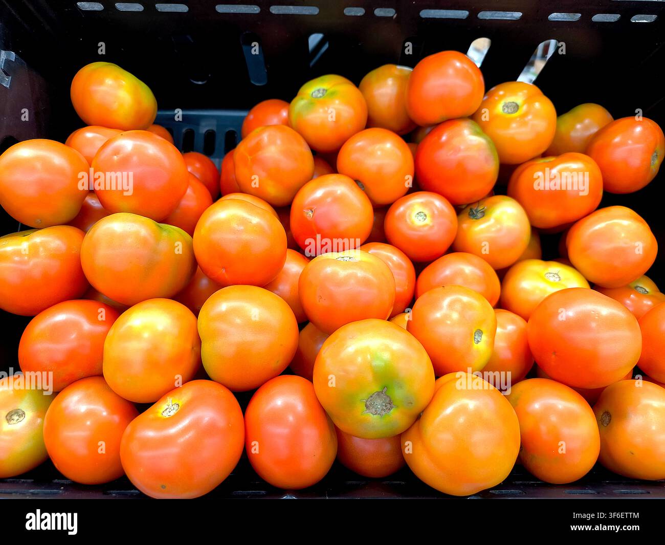 Massa di pomodori maturi in cassetta nera, colore rosso-arancio vivace, uso di fondo con prodotti freschi e stile concettuale. - Immagine stock catturata con smartphone
