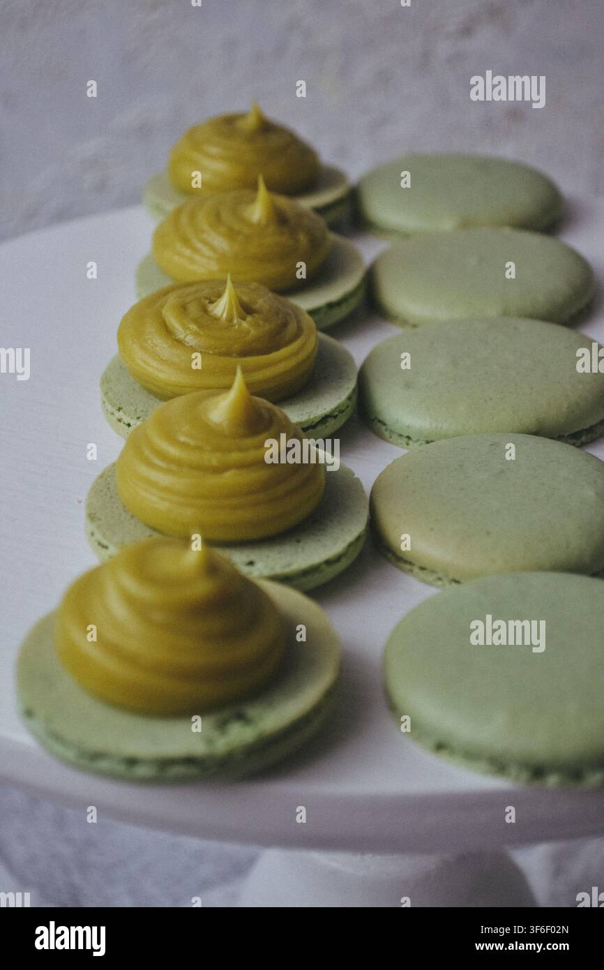 Pila di macaroncini ai pistacchi verdi con crema al burro e pistacchi tritati in primo piano Foto Stock